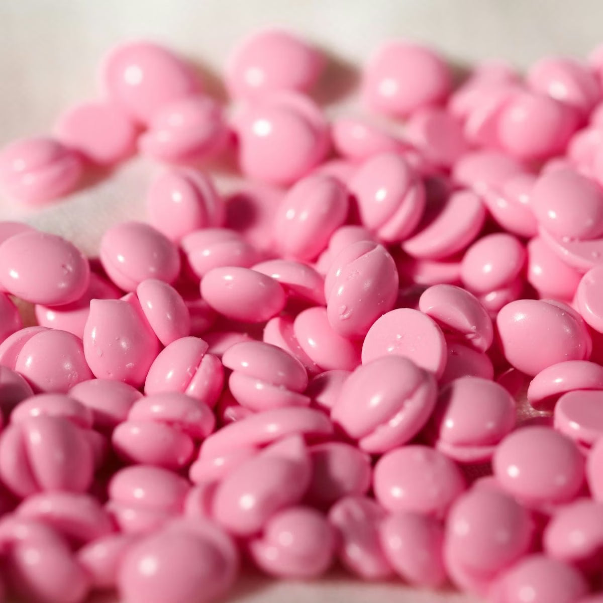 Close-up of pink chard wax beads on a white background
