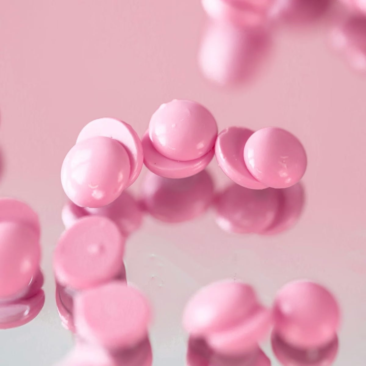 Close-up of pink hard wax beads on a pink background