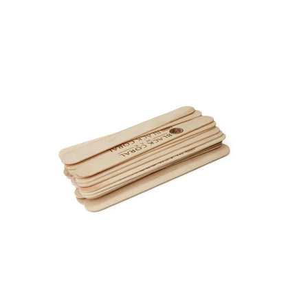 A small stack of light brown Wooden Waxing Sticks by Black Coral Wax USA is neatly aligned against a white background, with one stick featuring a printed logo. Ideal for professional waxing or crafts.
